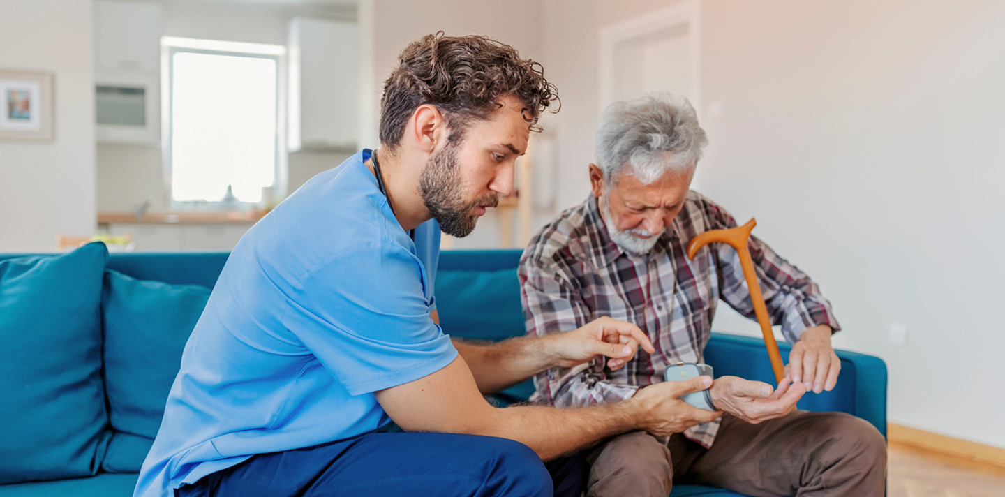 A caregiver gently assisting an elderly woman at home in Alabama